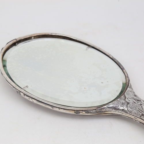 1124 - An unmarked Indian silver dressing table hand mirror, allover relief embossed animal and jungle deco... 