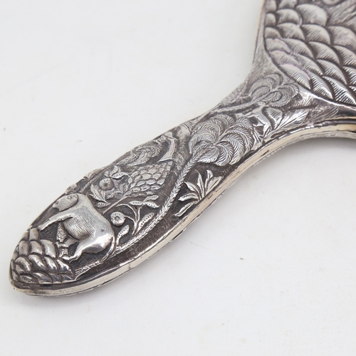 1124 - An unmarked Indian silver dressing table hand mirror, allover relief embossed animal and jungle deco... 