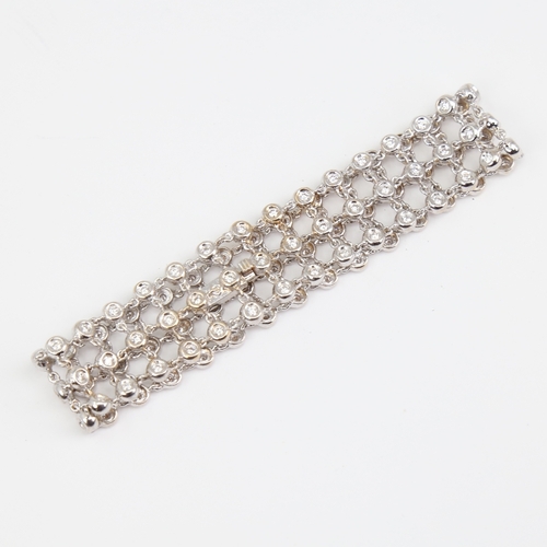 1130 - A modern 18ct white gold diamond triple-line bracelet, set with modern round brilliant-cut diamonds,... 