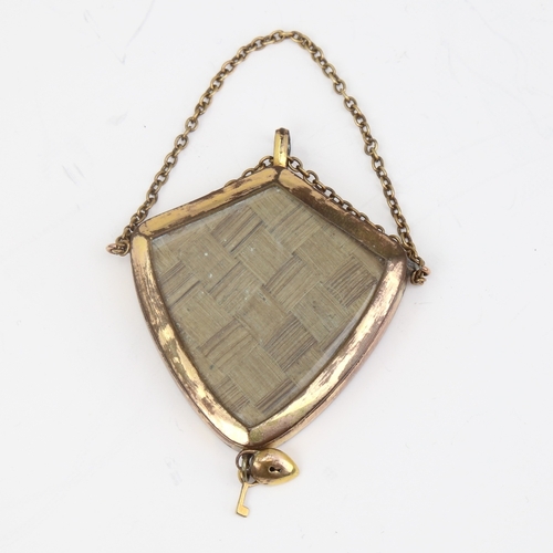 1138 - A Victorian unmarked yellow metal mourning pendant, shield form with bevel-glass panels and padlock ... 