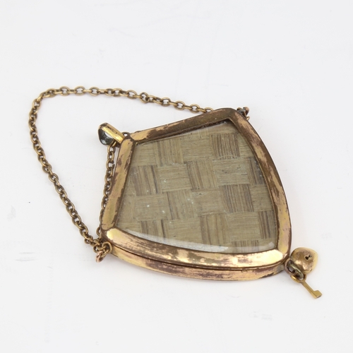 1138 - A Victorian unmarked yellow metal mourning pendant, shield form with bevel-glass panels and padlock ... 