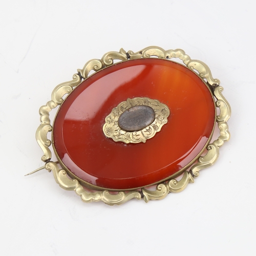 1139 - A large Victorian oval mourning brooch, unmarked yellow metal settings with red banded agate and vac... 