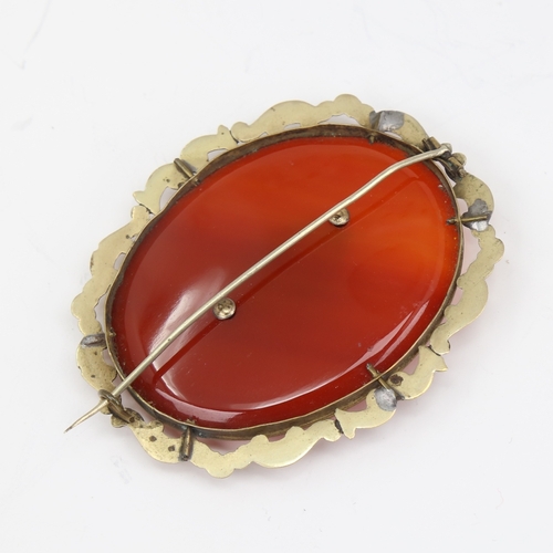 1139 - A large Victorian oval mourning brooch, unmarked yellow metal settings with red banded agate and vac... 