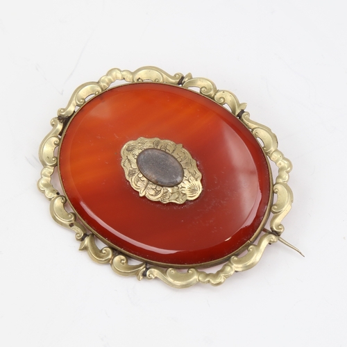 1139 - A large Victorian oval mourning brooch, unmarked yellow metal settings with red banded agate and vac... 