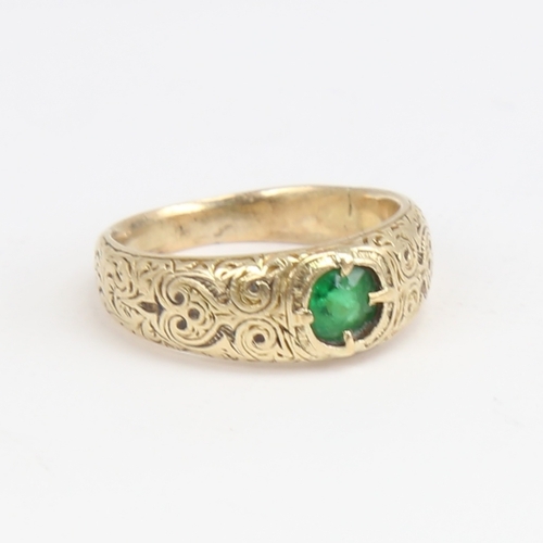 1164 - An Antique unmarked high carat gold green stone set ring, ornate engraved shoulders and shank, setti... 