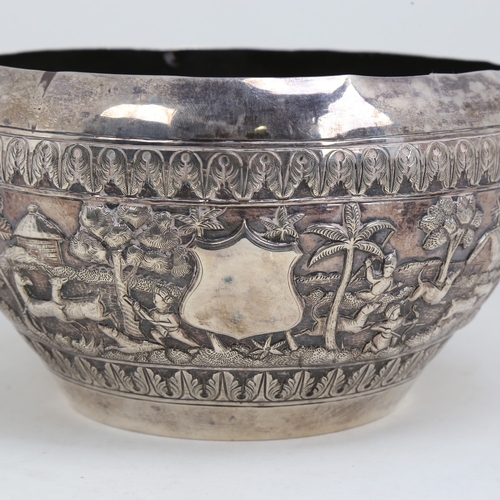 1200 - An early 20th century large Burmese silver rice bowl, relief embossed lion hunting and village scene... 