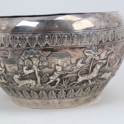 1200 - An early 20th century large Burmese silver rice bowl, relief embossed lion hunting and village scene... 