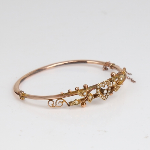 1204 - An early 20th century 9ct gold split-pearl heart and floral hinged bangle, hallmarks Chester 1905, s... 