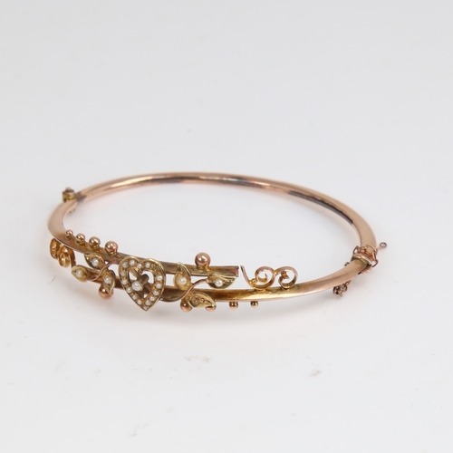 1204 - An early 20th century 9ct gold split-pearl heart and floral hinged bangle, hallmarks Chester 1905, s... 