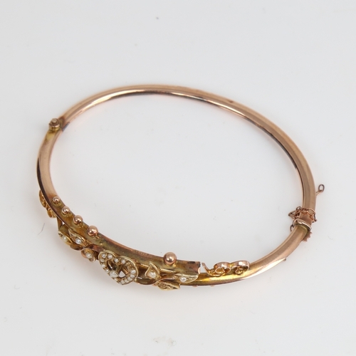 1204 - An early 20th century 9ct gold split-pearl heart and floral hinged bangle, hallmarks Chester 1905, s... 