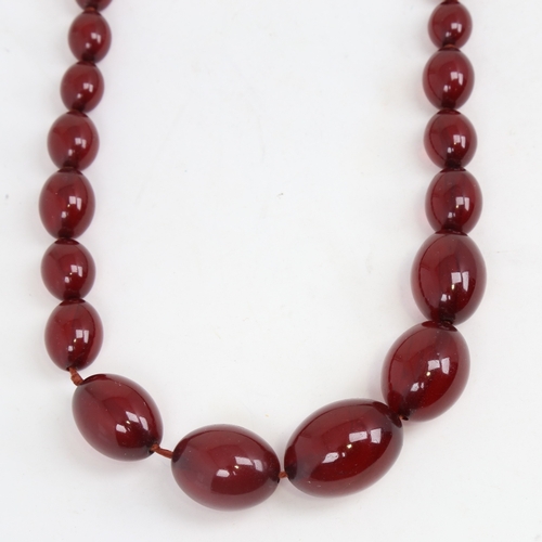 1214 - A long graduated single-strand cherry amber bead necklace, beads measuring from 31.4mm to 12.2mm, ne... 