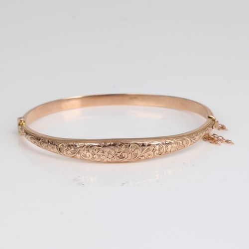 1220 - An early 20th century 9ct rose gold hinged bangle/bracelet, engraved floral and foliate decoration, ... 