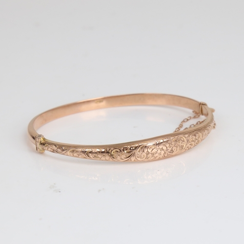 1220 - An early 20th century 9ct rose gold hinged bangle/bracelet, engraved floral and foliate decoration, ... 