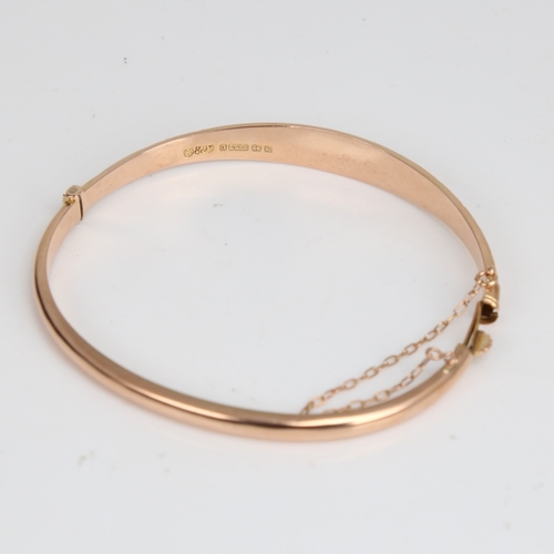 1220 - An early 20th century 9ct rose gold hinged bangle/bracelet, engraved floral and foliate decoration, ... 