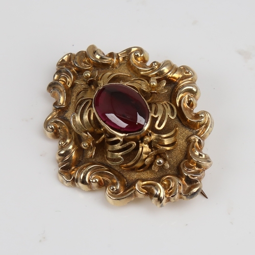 1293 - A Victorian unmarked gold cabochon garnet brooch, relief foliate border with textured ground and flo... 