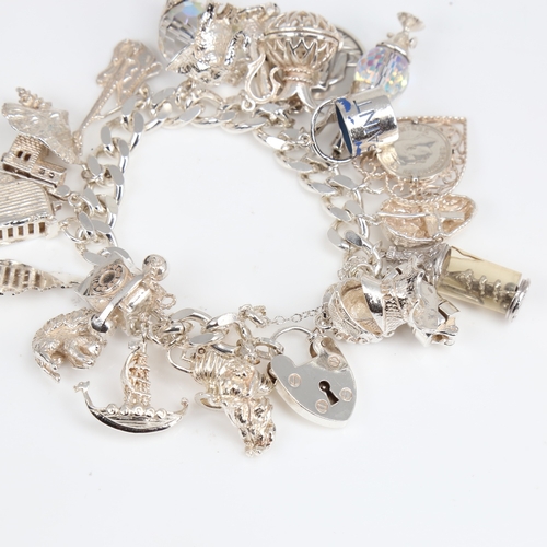 1391 - A late 20th century heavy sterling silver flat curb link charm bracelet, with heart padlock and fill... 