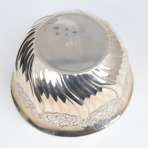 1408 - An Edwardian silver bowl, plain circular half fluted form with relief embossed floral decoration, by... 