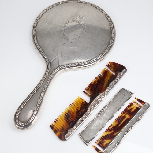 1410 - A silver-backed dressing table hand mirror, and 2 silver-mounted combs, mirror length 28cm (3)