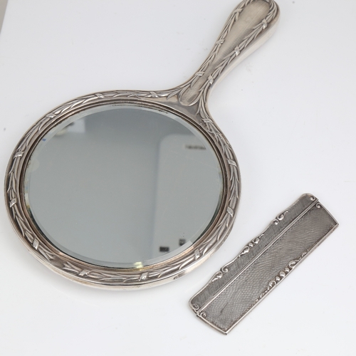 1410 - A silver-backed dressing table hand mirror, and 2 silver-mounted combs, mirror length 28cm (3)