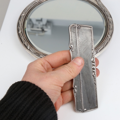 1410 - A silver-backed dressing table hand mirror, and 2 silver-mounted combs, mirror length 28cm (3)