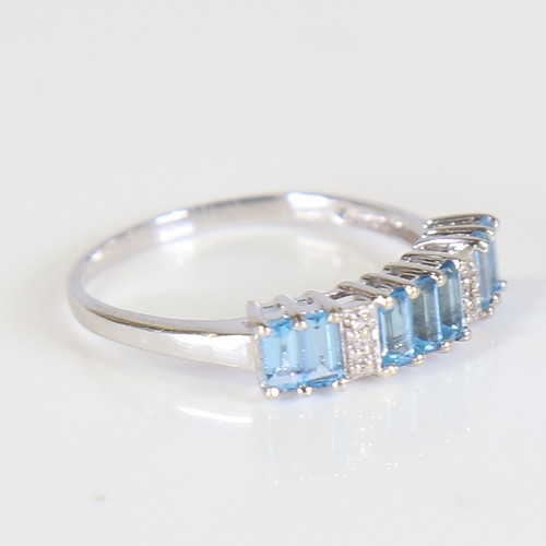 81 - A modern 9ct white gold blue topaz and diamond half hoop ring, set with baguette cut topaz and eight... 