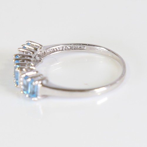 81 - A modern 9ct white gold blue topaz and diamond half hoop ring, set with baguette cut topaz and eight... 