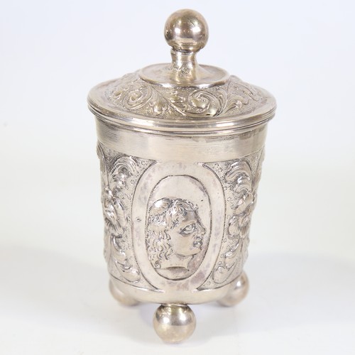 93 - A German silver beaker and cover, Hanau, relief embossed figural and foliate decoration on three bun... 