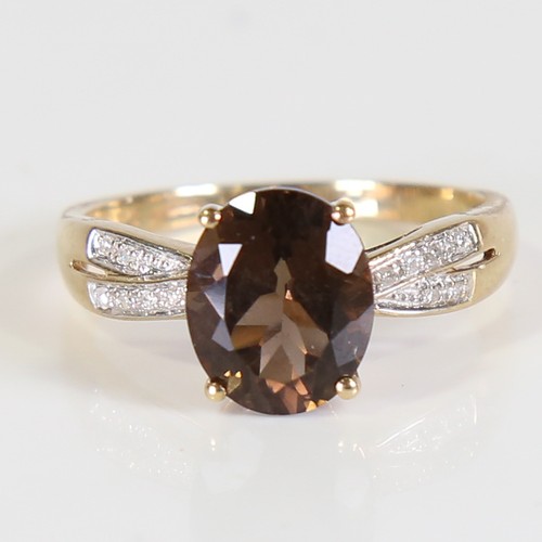 113 - A modern 9ct gold smoky quartz and diamond dress ring, set with oval mixed cut quartz and eight cut ... 