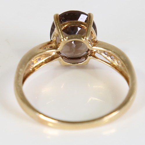 113 - A modern 9ct gold smoky quartz and diamond dress ring, set with oval mixed cut quartz and eight cut ... 