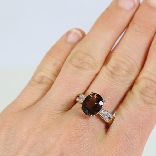 113 - A modern 9ct gold smoky quartz and diamond dress ring, set with oval mixed cut quartz and eight cut ... 