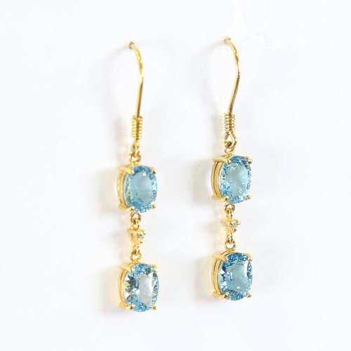 88 - A pair of modern handmade 18ct gold blue topaz and diamond drop earrings, set with oval mixed cut to... 