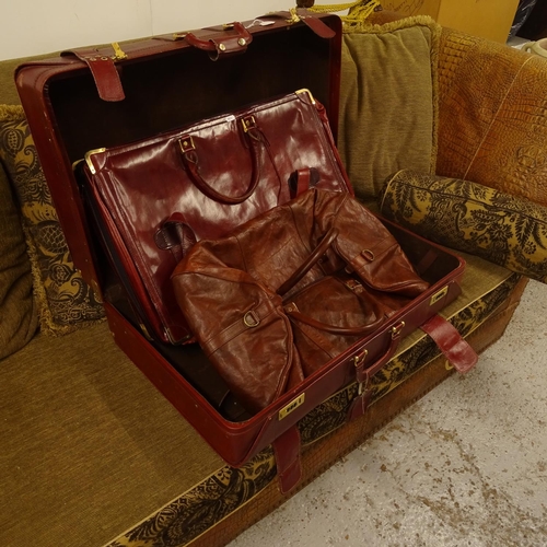 2058 - An Amiet burgundy suitcase, a burgundy leather suitcase, and brown leather holdall