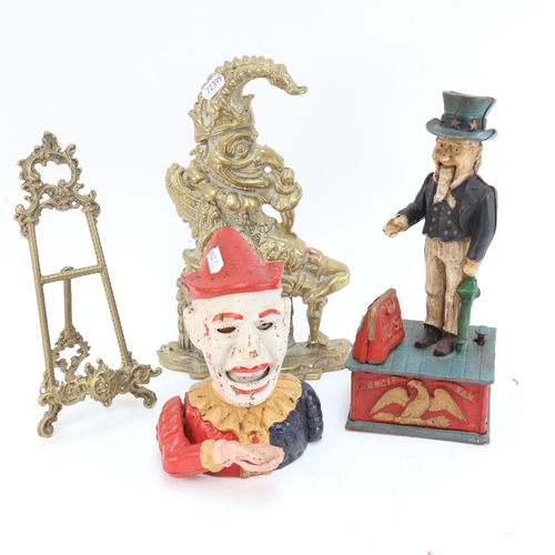 606 - A brass Mr Punch doorstop, 29cm, 2 novelty cast-iron money boxes, and a small picture easel