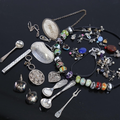 887 - A box containing silver-mounted charms, silver earrings and costume jewellery, a mustard spoon etc