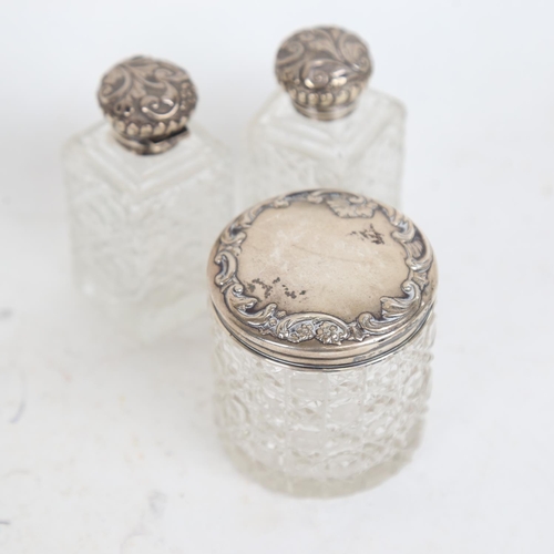 939 - 3 cut-glass and embossed silver-mounted scent bottles, and a silver-topped dressing table jar