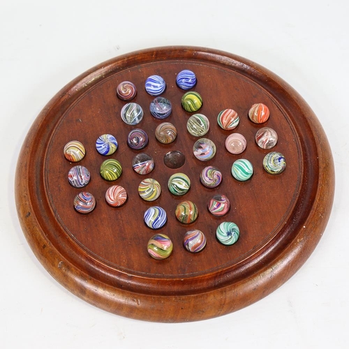 133 - A 19th century turned wood solitaire board and marbles, including onion skins, diameter 26cm