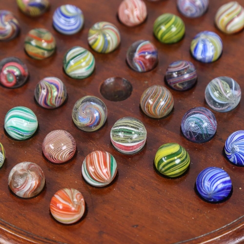 133 - A 19th century turned wood solitaire board and marbles, including onion skins, diameter 26cm