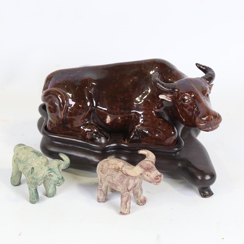 171 - A Chinese brown treacle glaze pottery buffalo on hardwood stand, length 21cm, and 2 miniature potter... 