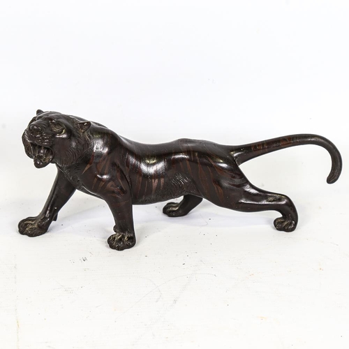 303 - A Japanese patinated bronze striped tiger, seal mark under base, length 24cm