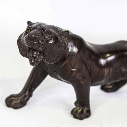 303 - A Japanese patinated bronze striped tiger, seal mark under base, length 24cm