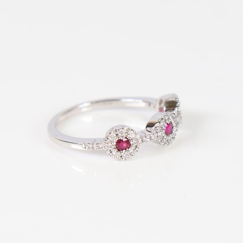 609 - A modern 18ct white gold ruby and diamond triple cluster dress ring, set with round-cut rubies and m... 