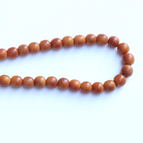 242 - A string of honey coloured natural horn beads, possibly rhino horn