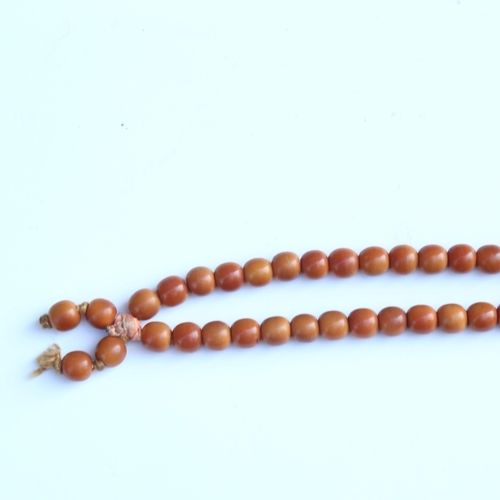 242 - A string of honey coloured natural horn beads, possibly rhino horn