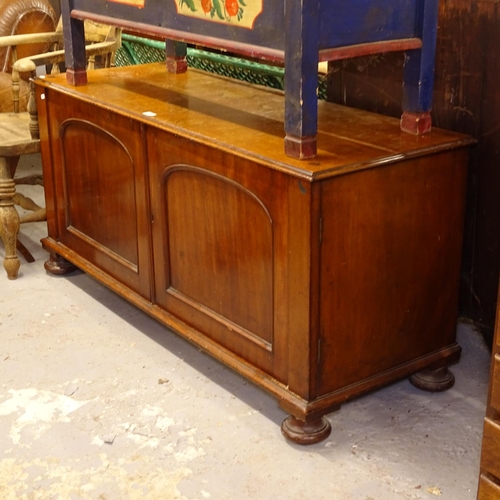 2436 - A Victorian mahogany low cupboard, with panelled doors, on bun feet, W137cm, H64cm, D50cm