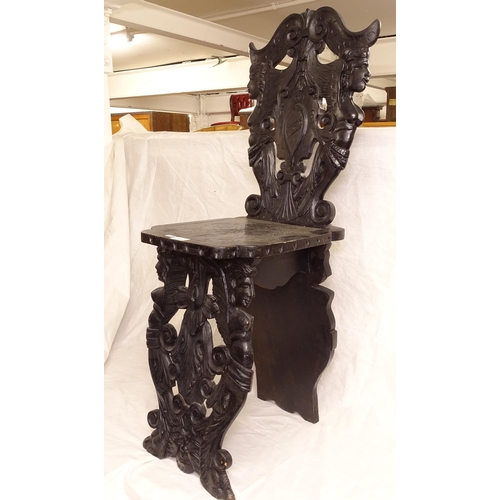 2484 - An Italian carved ebonised hall chair, with winged figural panelled back