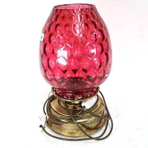 549 - A brass oil lamp with cranberry glass light shade, height 42cm (A/F)