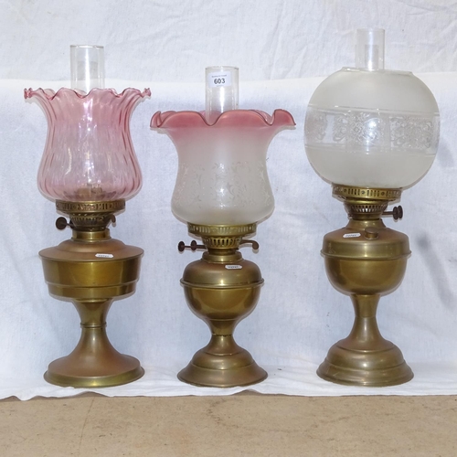 603 - 3 brass oil lamps with chimneys and glass shades, tallest 53cm