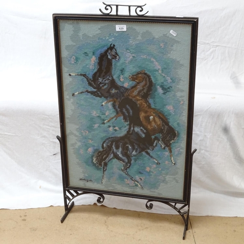 629 - A wrought-iron framed glazed fire screen, with cross stitch design of horses, height 87cm