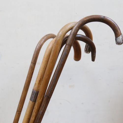 43 - Embossed brass stick stand, containing 5 walking sticks with silver mounts