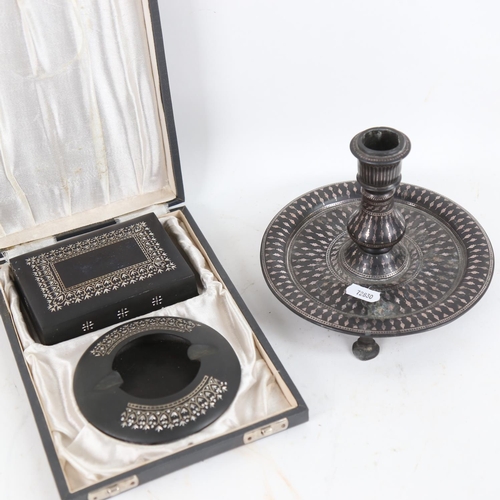 112 - A Middle Eastern silver inlaid oxidised metal candlestick, and a similar cased smoker's set (3)